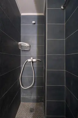 a bathroom with a shower with black tiles at Retro-Modern Echoes in Athens