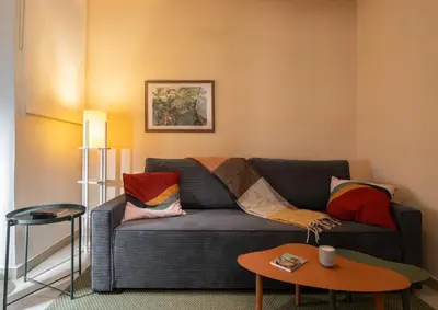 a living room with a gray couch with colorful pillows at Retro-Modern Echoes in Athens