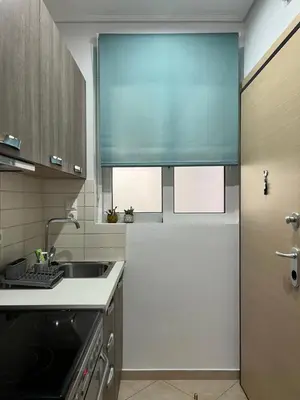 a kitchen with a sink and a window with a blue curtain at Central Stay in Athens in Athens