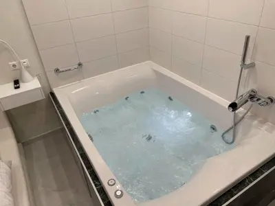 a bath tub filled with blue water in a bathroom at Bubble & Relax- Private Jacuzzi Near Acropolis- Fix Metro 180m in Athens