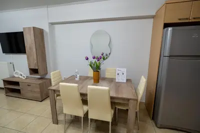 a kitchen with a wooden table with chairs and a refrigerator at Ηappy Apartment 1 in Athens