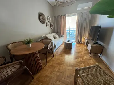 a living room with a bed and a table and a television at BFC Glufada in Athens