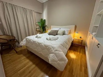a bedroom with a large bed with white sheets at BFC Glufada in Athens
