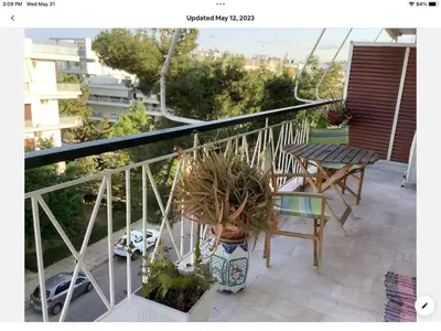 a woman standing on a balcony with a plant at Sunshine place in Glyfada in Athens