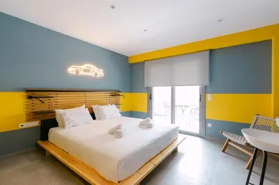 a bedroom with a large bed with yellow and blue walls at 11 Reasons Why Metaxourgeio in Athens