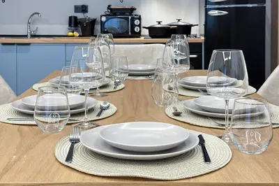 a wooden table with plates and wine glasses on it at Dione Elegant Apartment Near Acropolis in Athens