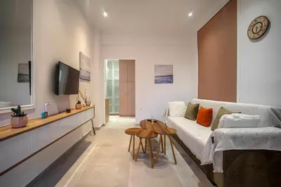 a living room with a white couch and a tv at Acropolis Sneak peak 5th floor in Athens