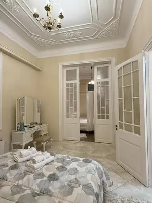 a white bedroom with a bed and a mirror at Neoclassical Royal Palace next to Acropolis in Athens