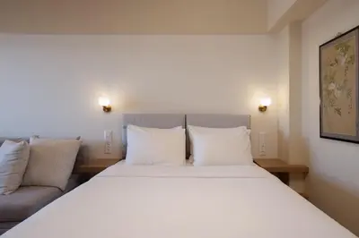 a bedroom with a large white bed and a couch at Aelia-Smart central beach flat in Athens