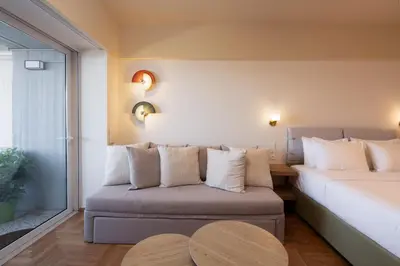 a bedroom with a bed and a couch and a window at Aelia-Smart central beach flat in Athens