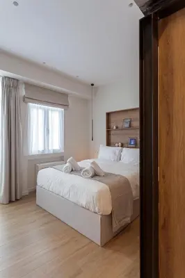 a bedroom with a large bed with a window at Heart of Athens Suites in Athens