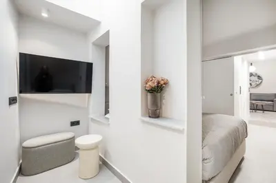 a white bedroom with a bed and a tv at Plaka Clio Apartment by A&A Residences in Athens