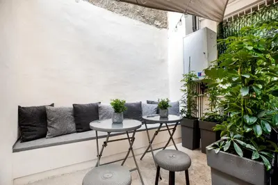 two tables and a bench in a room with plants at Plaka Clio Apartment by A&A Residences in Athens