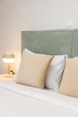 a bed with white pillows and a green headboard at Stylish 2-Bedroom Apartment with Big Terrace in Athens in Athens