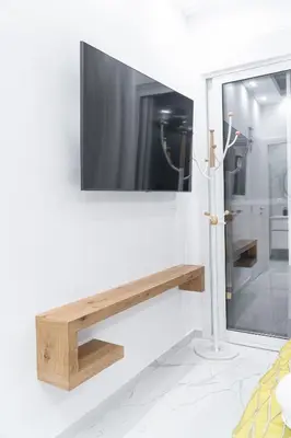 a tv hanging on a wall with a wooden shelf at Diamond Downtown Kolonaki in Athens