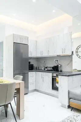 a kitchen with white cabinets and a table and chairs at Diamond Downtown Kolonaki in Athens
