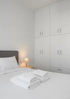 a white bed with white cabinets and towels on it at Bivium Suites by LobbySquare in Athens