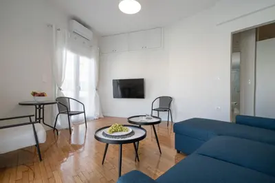 a living room with a blue couch and tables and chairs at Bivium Suites by LobbySquare in Athens