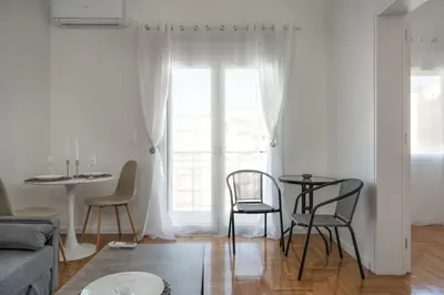 a living room with a table and chairs and a window at Bivium Suites by LobbySquare in Athens