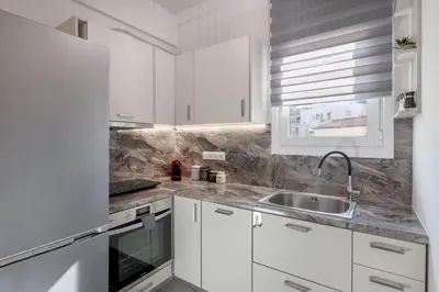 a white kitchen with white cabinets and a sink at The HostMaster Timeless Elegance in Athens