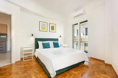 a white bedroom with a large white bed and wooden floors at 3 Bedroom Gem at METRO in Athens