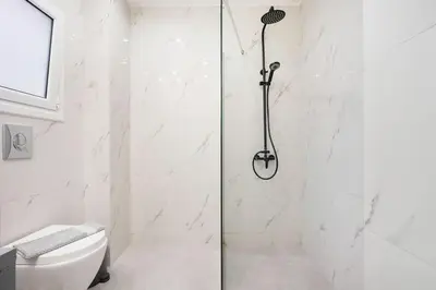 a white bathroom with a shower and a toilet at 3 Bedroom Gem at METRO in Athens
