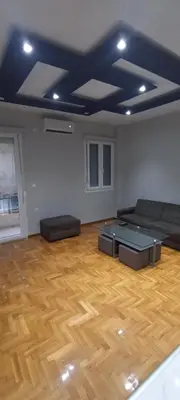 a living room with a couch and a wooden floor at Michali's Sepolia Agios Meletis Apartment in Athens