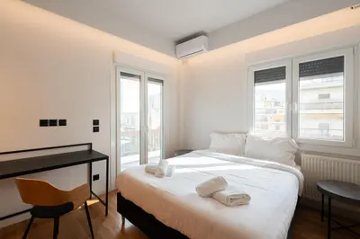 a bedroom with a bed with a desk and two windows at LIV - Spacious Flat for Friends & Family in Athens