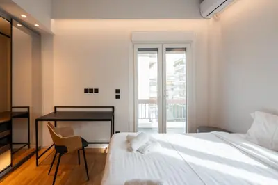 a bedroom with a bed and a desk and a window at LIV - Spacious Flat for Friends & Family in Athens