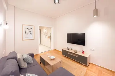 a living room with a couch and a tv on a wall at Radiant Apt near Lycabettus in Athens