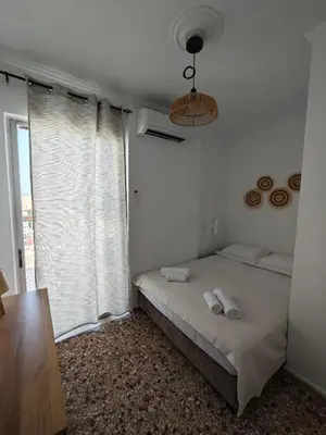 a bedroom with a bed and a large window at Aspa and Alex penthouse retreat in Koropíon