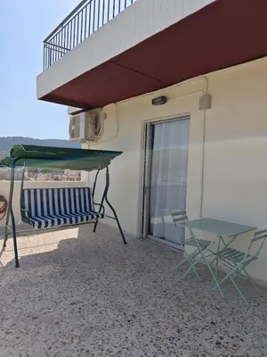 a table and a chair on the balcony of a building at Aspa and Alex penthouse retreat in Koropíon