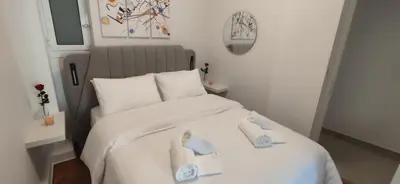 a bedroom with a white bed with towels on it at Cozy Νest Athens in Athens