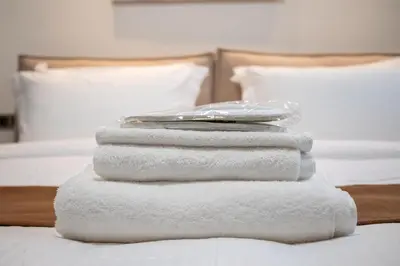 a stack of towels sitting on top of a bed at Athenee Suites in Athens