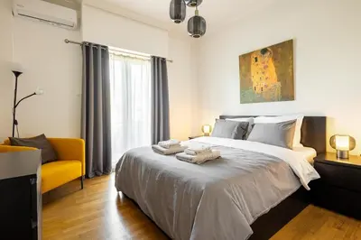 a bedroom with a large bed and a yellow chair at Bright and breezy by the sea in Athens