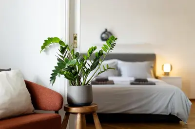a bedroom with a bed with a potted plant on a stool at Bright and breezy by the sea in Athens