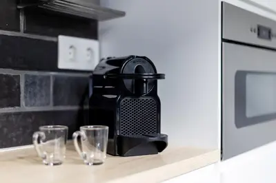 a black coffee maker sitting on a counter with two glasses at Bright and breezy by the sea in Athens