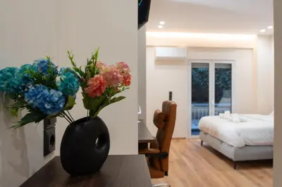 a black vase with flowers on a table in a bedroom at Luxury Suite 100m from Shore and Tram in Athens