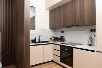 a kitchen with white counters and wooden cabinets at Luxury Suite 100m from Shore and Tram in Athens