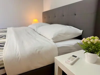 a bed with white sheets and a table with a remote control at Kalithea Spartis appartment in Athens