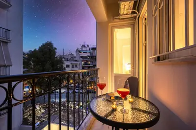 a table on a balcony with two glasses of wine at Acropolis Retreat Stay in Style in Athens