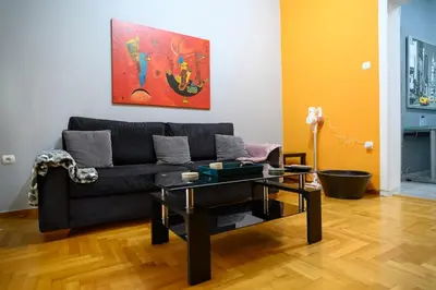 a living room with a black couch and a table at Cosy Pangrati Urban Retreat in Athens