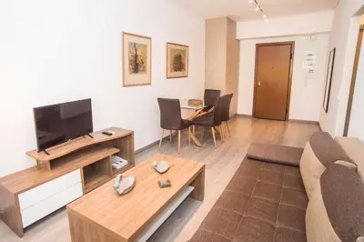 a living room with a couch and a tv and a table at Beachside Bliss Central 1-Bedroom in Glyfada in Athens