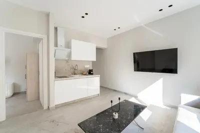 a kitchen with white cabinets and a tv on the wall at Luna Luxury Suite - close to Acropolis in Athens