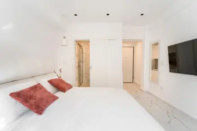a white bedroom with a white bed with two red pillows at Honey Luxury Suite - close to Acropolis in Athens