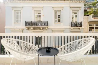 a table and chairs on a balcony with a building at Honey Luxury Suite - close to Acropolis in Athens