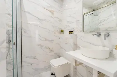 a white bathroom with a sink and a shower at Honey Luxury Suite - close to Acropolis in Athens