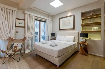 a bedroom with a large white bed and a chair at Artemis - Luxenia Suites in Athens