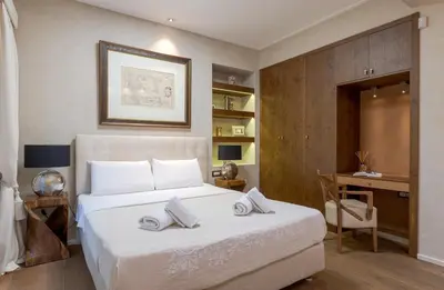 a bedroom with a large white bed with a desk at Artemis - Luxenia Suites in Athens
