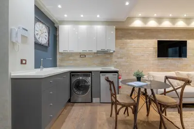 a kitchen with a washing machine and a table and chairs at Artemis - Luxenia Suites in Athens